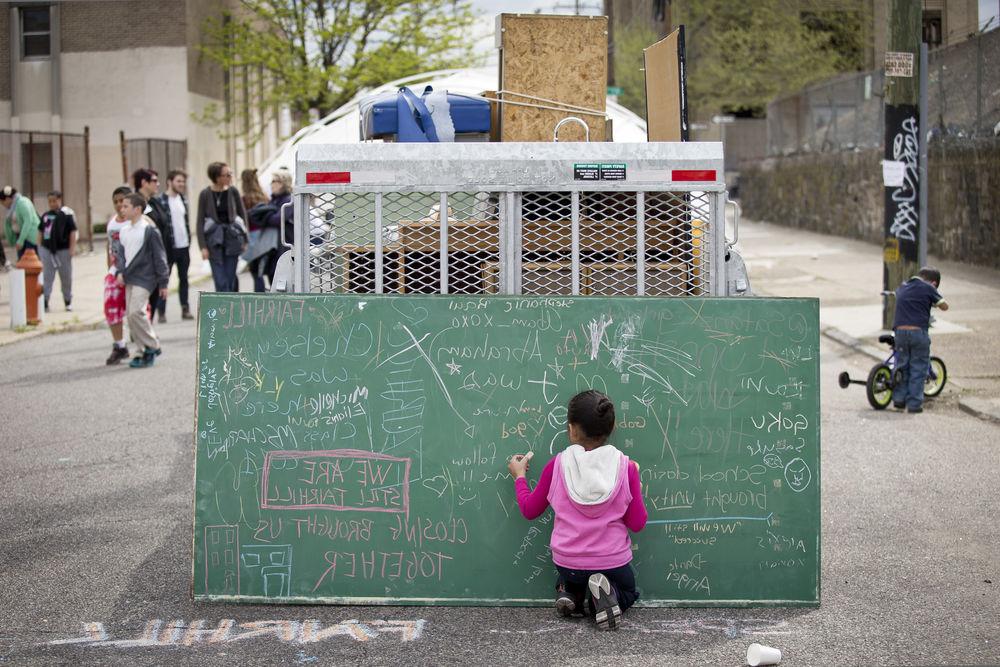 在繁忙的街道上，一个孩子在黑板上写字